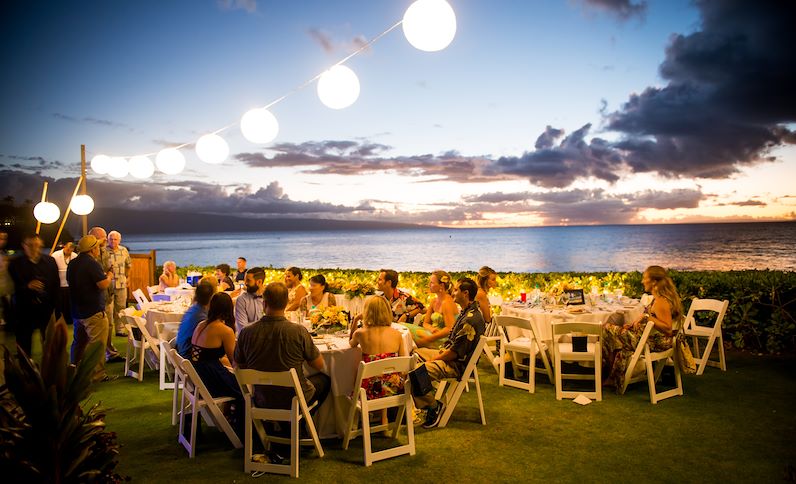 Beachside reception dinner with many guests at sunset