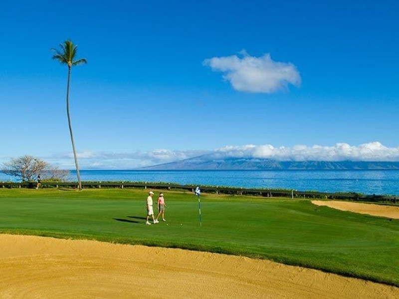 Two golfers walk the greens that are oceanside at the Royal Lahaina